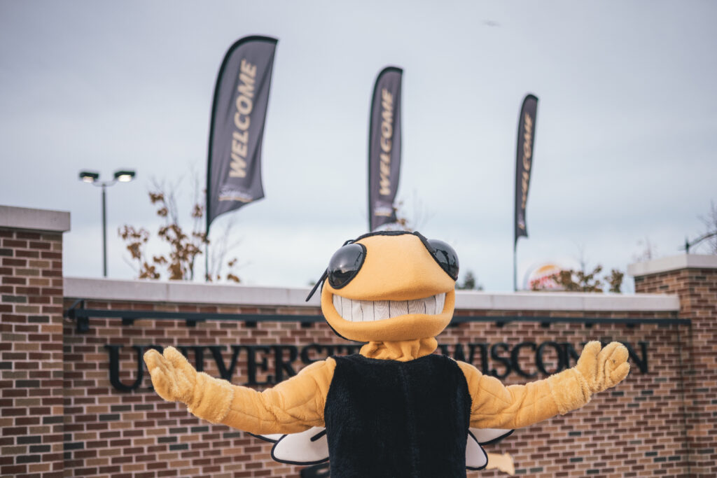 Mascot Buzz standing in front of the UW-Superior entrance sign