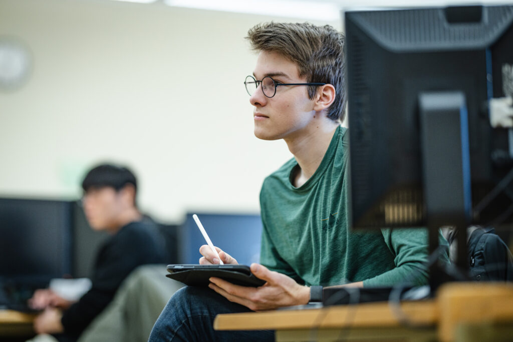 Student sitting through financial aid lecture taking notes