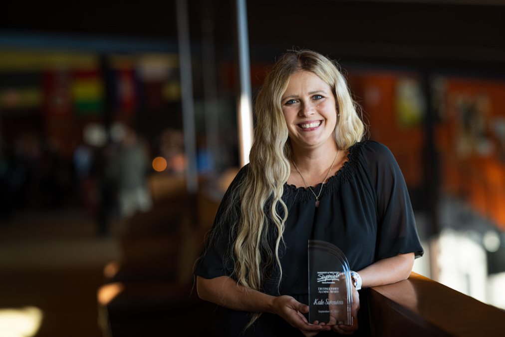 A photo of an alumni holding her Distinguished Alumni Award plaque.