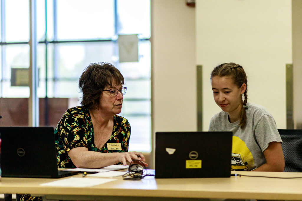 Staff member helping a student on a computer