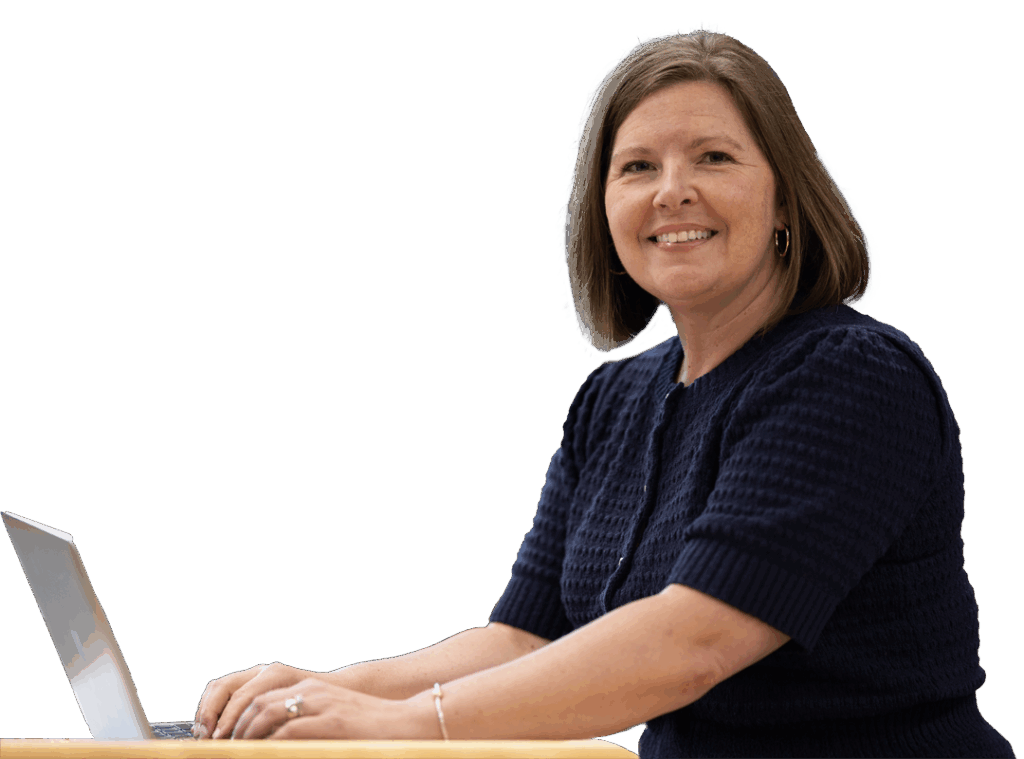 Jamie White-Farnham sits at a desk and smiles while typing on a laptop at the University of Wisconsin-Superior.