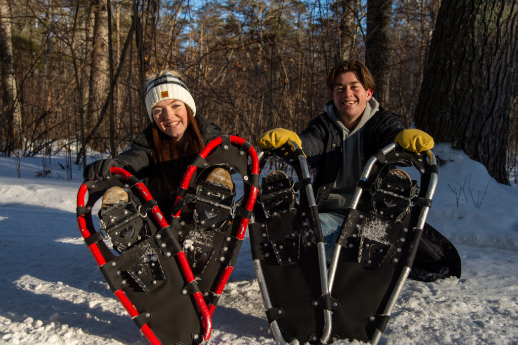 Students sitting on the ground with snowshoes on