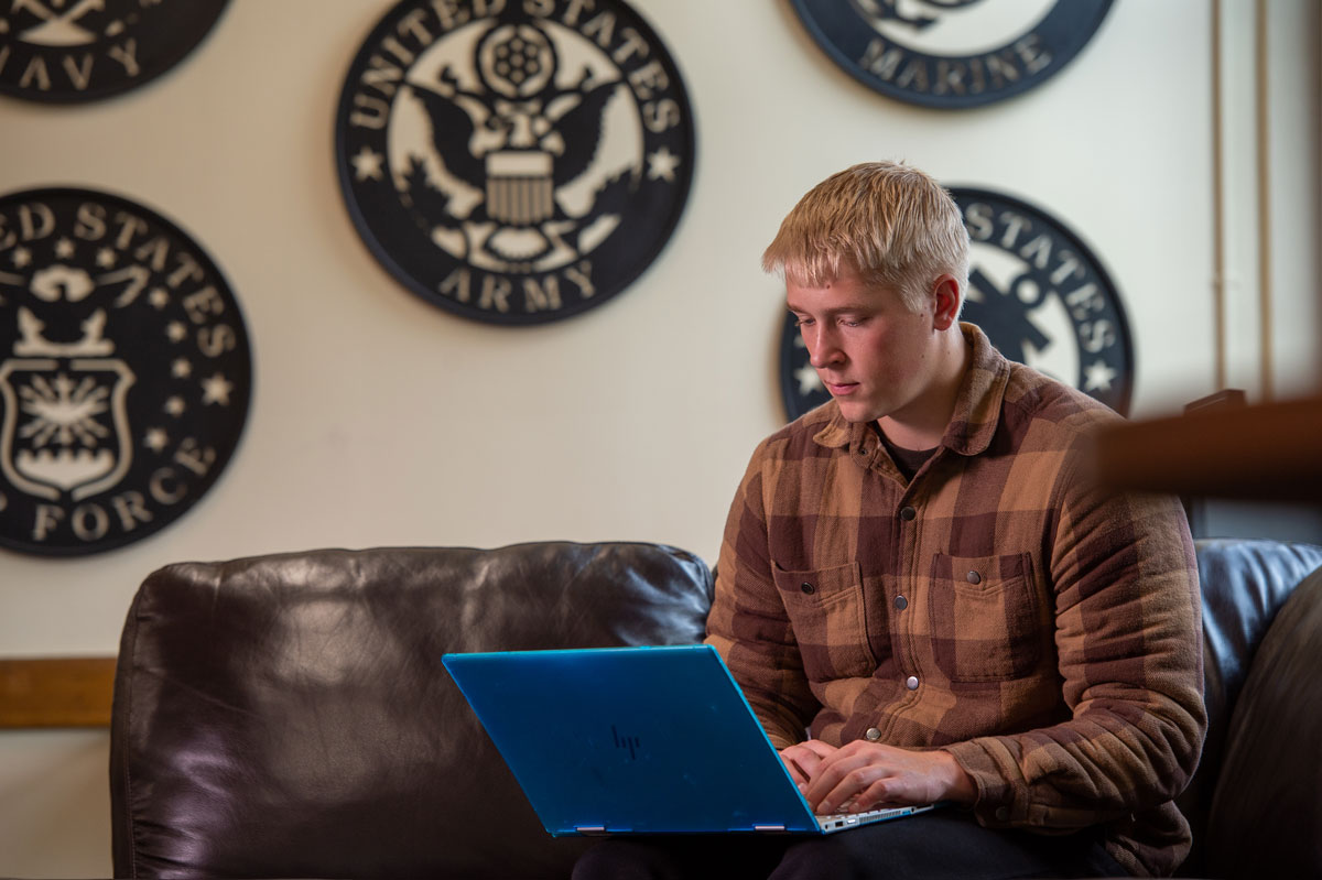 A University of Wisconsin-Superior student sits on a couch using a laptop.