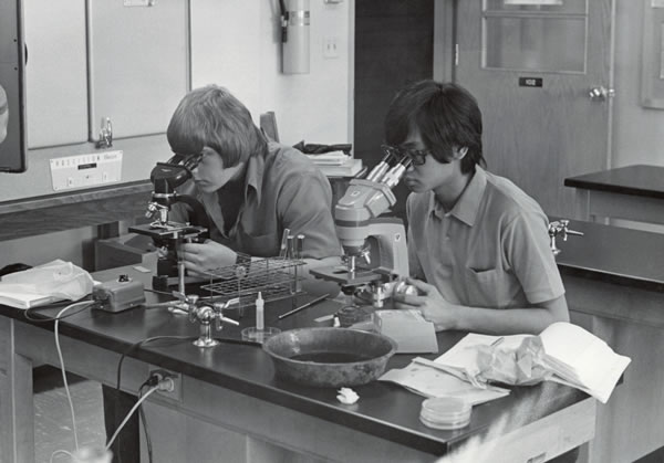 Black and white photo of students looking in microscopes