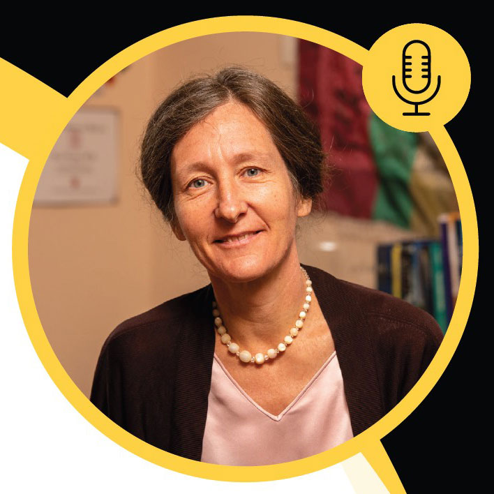 A woman with brown hair pulled back, wearing a pearl necklace, a light pink blouse, and a dark cardigan, smiles at the camera. The circular yellow border and microphone icon hint at upcoming events and activities shell be sharing.