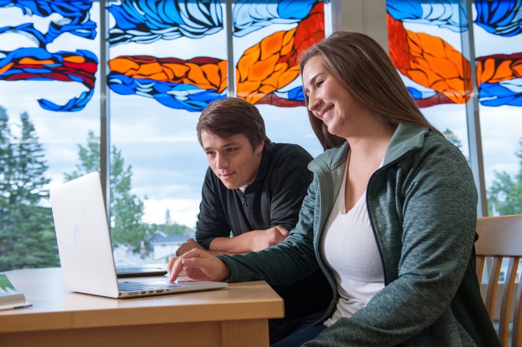 Two students video conferencing on a laptop